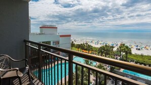 Un balcon avec vue sur une plage et une piscine.