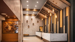Un espace d’accueil doté d’un comptoir en marbre, de quelques éléments décoratifs en bois et d’un mur en briques.