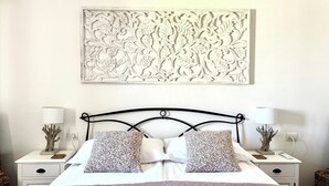 A bedroom with a bed, two nightstands, a wall-mounted artwork, and a patterned bedspread. - Casa Caterina - Spacious Sea-View Apart (La Ciaccia)