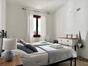 A bedroom with two beds, a bedside table with a lamp, a dresser, and a window with curtains. - Casa Caterina - Spacious Sea-View Apart (La Ciaccia)