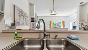 Uma cozinha moderna com uma pia dupla, um ventilador de teto e obras de arte nas paredes.