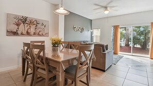 Uma sala de jantar com mesa e cadeiras, um ventilador de teto e um quadro na parede.