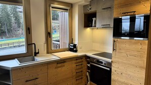 A modern kitchen with wooden cabinetry, a built-in oven, and a microwave. - Le Morel 35 - Lovely apartment completely renovated (LES AVANCHERS VALMOREL)