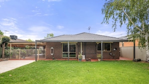 A single-story brick house with a tiled roof, a covered porch, and a well-maintained lawn. - Charming 3-bed Family Home With Amazing Garden (Melbourne)