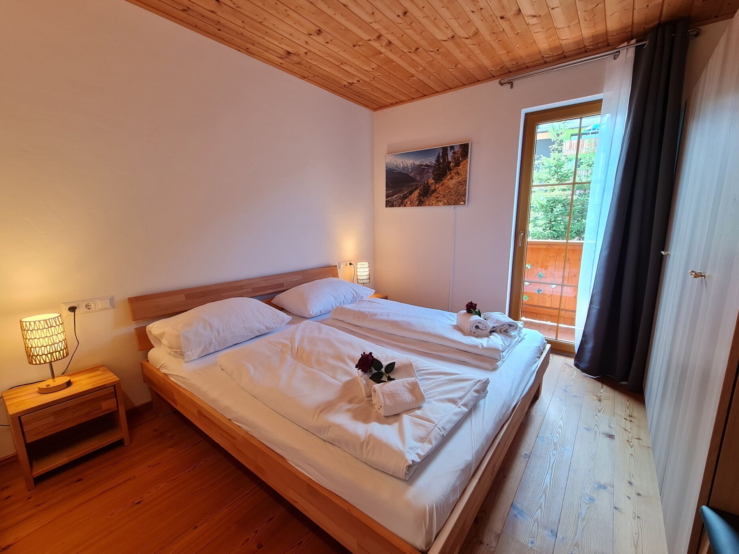 Un lit double avec du linge de lit blanc, une lampe de chevet et un tableau au mur.