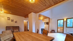 Ein geräumiger Raum mit einem großen Holztisch, einer Holzbalkendecke und Blick auf einen Balkon mit Holzbalkon.
