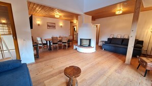 Ein geräumiges Wohnzimmer mit Holzboden, Kamin, Essbereich und einer Couch.
