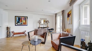 A spacious living room with a sofa set, a dining table, and a painting on the wall. - Bright Apartment - 2br/4p - Muette/passy - Trocadero (Paris)