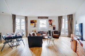 A modern living room with a dining area, large windows, and a flat-screen TV. - Bright Apartment - 2br/4p - Muette/passy - Trocadero (Paris)