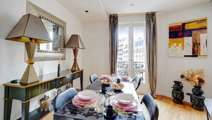 A dining room with a long table set for four, a mirror above, and a window with curtains. - Bright Apartment - 2br/4p - Muette/passy - Trocadero (Paris)