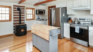 Une cuisine moderne équipée d’un poêle à bois, d’appareils électroménagers en acier inoxydable et d’un chariot gris.