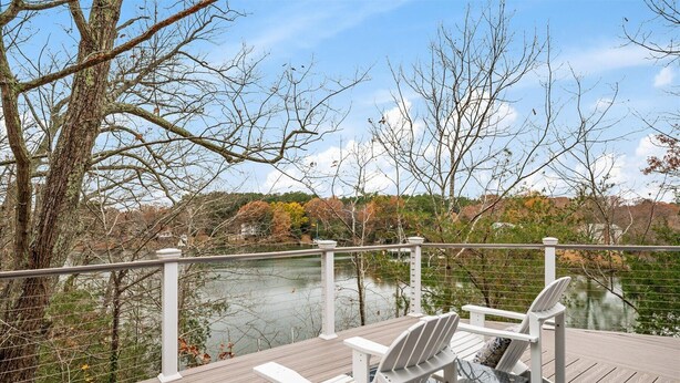 Une terrasse avec deux fauteuils Adirondack donnant sur un lac, entourée d’arbres et dotée d’une rambarde.
