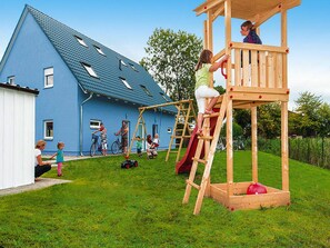A playground with a wooden climbing structure and a slide. - Ferienhaus Hyggelig in Seehausen am Oberuckerse (Oberuckersee)
