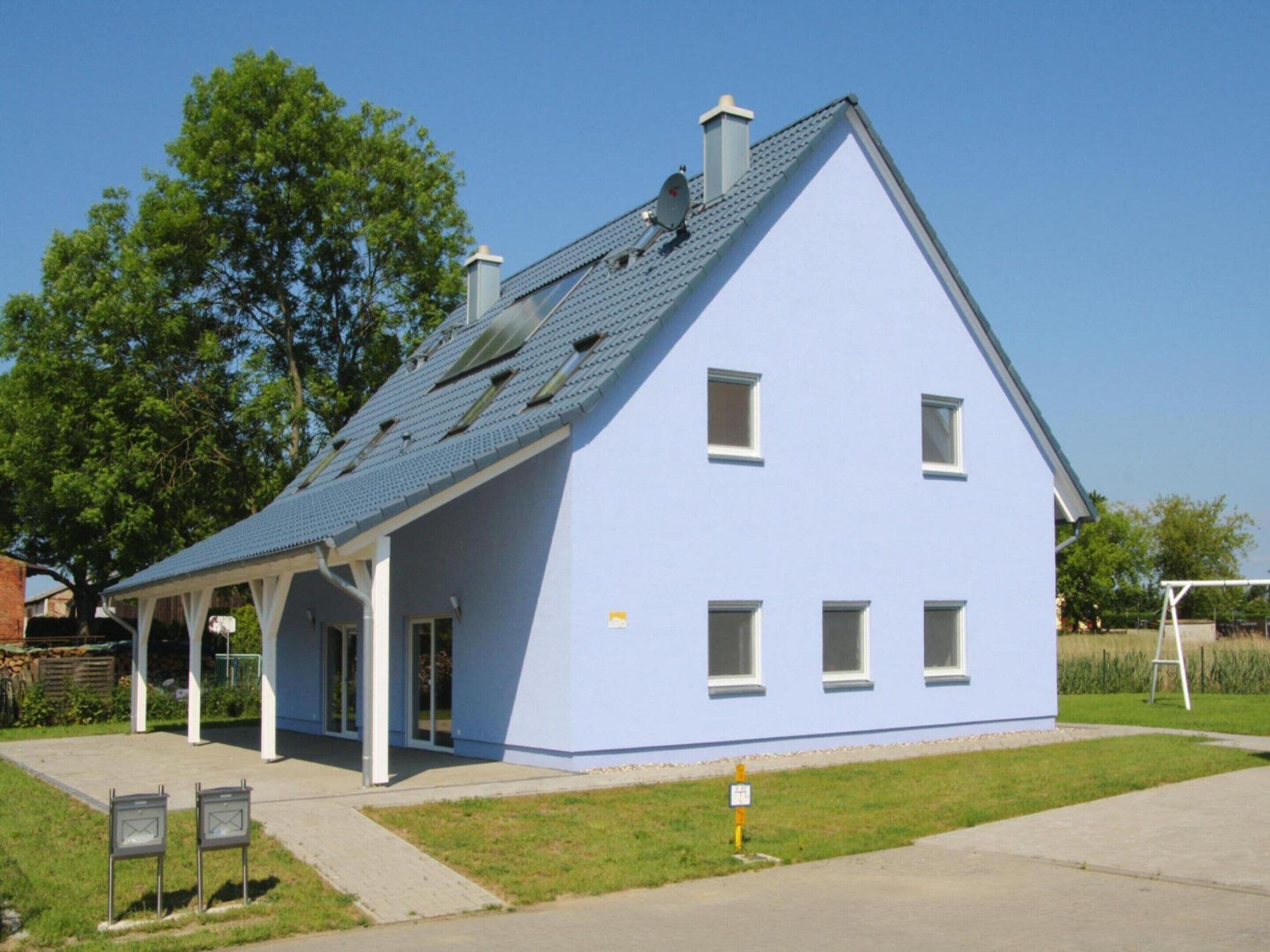 Una casa a due piani con tetto spiovente, un portico coperto e un piccolo giardino.
