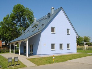 A two-story house with a sloped roof, a covered porch, and a small garden area. - Ferienhaus Hyggelig in Seehausen am Oberuckerse (Oberuckersee)