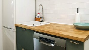 A kitchen with a white refrigerator, a sink with a faucet, a wooden countertop, and a dishwasher. - 4 Star Holiday Home in Slagelse (Slagelse)