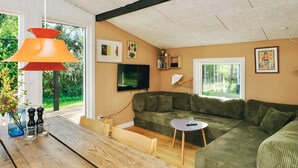 A modern living room with a sectional sofa, a wooden coffee table, a TV, and a large window. - 4 Star Holiday Home in Slagelse (Slagelse)