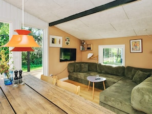 Una sala de estar moderna con un sofá verde, una mesa de centro de madera y un amplio ventanal con vistas a zonas verdes.