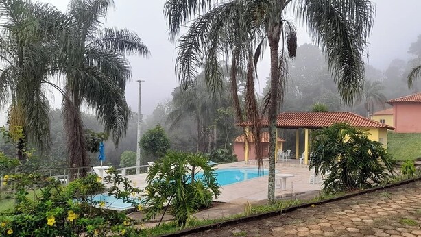 Un espace piscine avec une eau cristalline, entouré de palmiers et bordé d’un bâtiment au toit rouge.