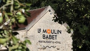 Een gebouw van steen met een bord waarop staat: Le Moulin Babet Restaurant & Hotel.