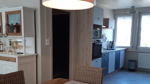 Ein Essbereich mit einem Holztisch, Korbstühlen und einer Pendelleuchte.