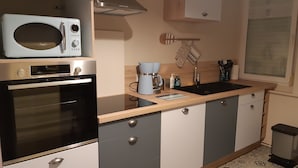 Eine kompakte Küche mit Mikrowelle, Backofen und Kaffeemaschine.
