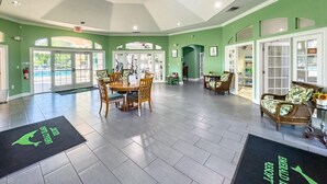Um hall espaçoso com teto alto, área de jantar central e um espaço de estar com móveis de vime.