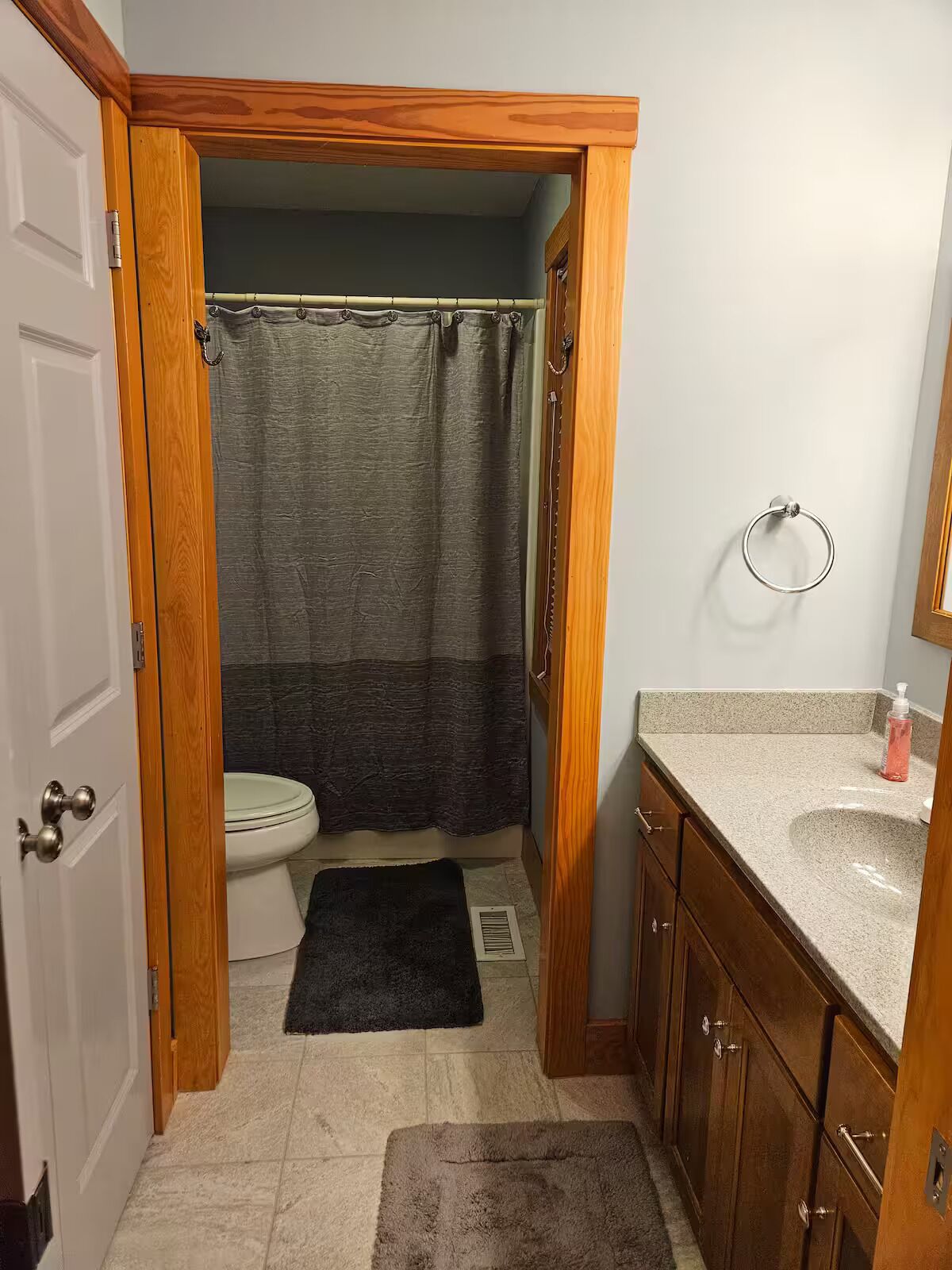 Un baño con inodoro, cortina de ducha, lavabo y armarios de madera.
