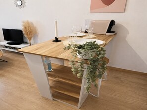 A modern dining area with a wooden table, white plates, and a potted plant. - Couple Stay by the French Riviera (Vallauris)