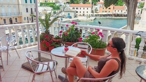 A balcony with a view of a body of water, potted plants, and outdoor seating.
