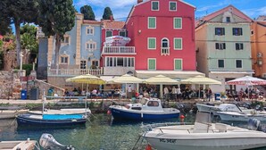 A harbor with boats, a red building with green shutters, and a blue building with a sign.