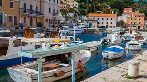A marina with various boats docked, a glass table with items on it, and buildings in the background. - Pansion Saturn / Pansion Saturn room 14 (Veli Lošinj)