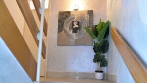 A staircase with a wooden handrail, a potted plant, and a framed artwork on the wall. - Pansion Saturn / Pansion Saturn room 14 (Veli Lošinj)