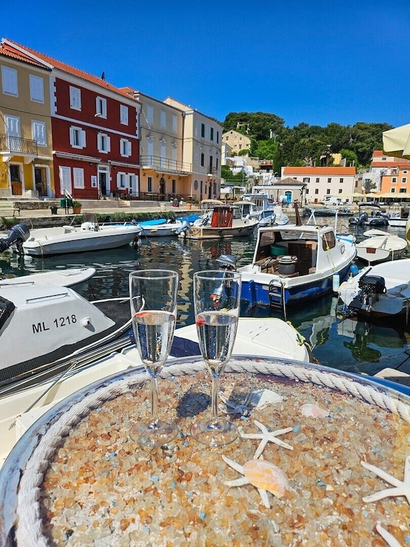 Un port de plaisance avec des bateaux amarrés, une table avec un verre d’eau et des bâtiments en arrière-plan.
