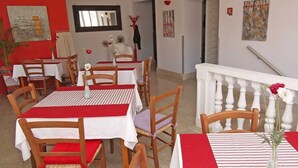 A dining area with multiple tables and chairs, a staircase with a white balustrade, and artwork on the walls. - Pansion Saturn / Pansion Saturn soba 26 -sea view (Veli Lošinj)