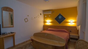 A hotel room with a wooden bed, a desk with a television, and a wall-mounted air conditioner. - Pansion Saturn / Pansion Saturn soba 26 -sea view (Veli Lošinj)