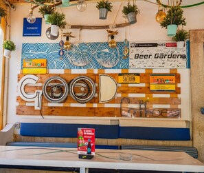 A wall with various signs and decorations, including a large 'GOOD' sign made of wooden planks and bicycle wheels, surrounded by potted plants and hanging light bulbs. - Pansion Saturn / Pansion Saturn soba 25 (Veli Lošinj)