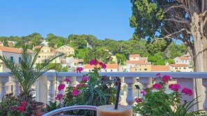 Una mesa con una bebida y un postre en un balcón con vistas a un pueblo.