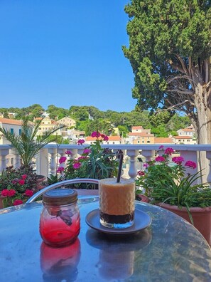 A table with a drink and a dessert on a balcony overlooking a town. - Pansion Saturn / Pansion Saturn soba 25 (Veli Lošinj)