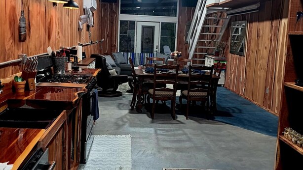 Eine rustikale Küche mit Holzschränken, ein Essbereich mit Tisch und Stühlen sowie eine Treppe, die zu einer oberen Ebene führt.