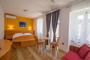 Ein Hotelzimmer mit Bett, Nachttischen, einem Sessel, einem kleinen Tisch und einer Couch.