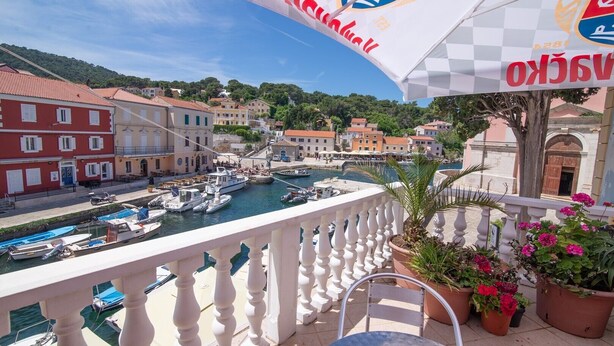 A balcony with a view of a harbor, potted plants, and a flag. - Pansion Saturn / Pansion Saturn soba 16 - seaview (Veli Lošinj)