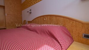 A bedroom with a wooden headboard, a bed with a patterned bedspread, a bedside table, and a wall-mounted clock. - Pansion Saturn / Pansion Saturn 15 (Veli Lošinj)