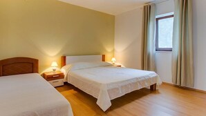 Ett hotellrum med två separata sängar, sänggavlar i trä, sängbord med lampor och ett fönster med gardiner.