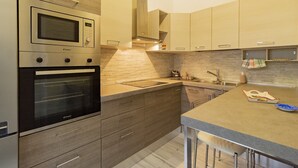 Una cocina moderna con horno empotrado, microondas y una campana extractora de acero inoxidable.