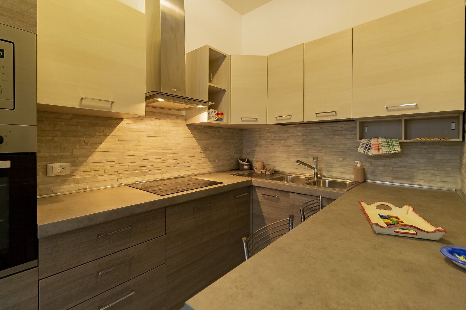 A modern kitchen with a built-in stove, stainless steel sink, and wooden cabinets.