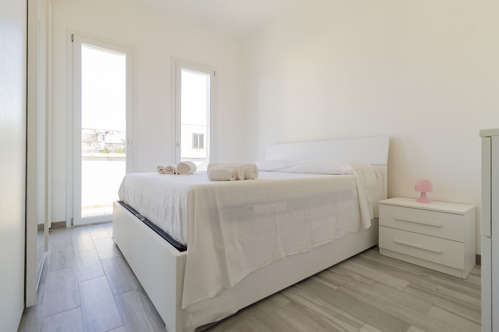 A bedroom with a bed, a nightstand, and a window.