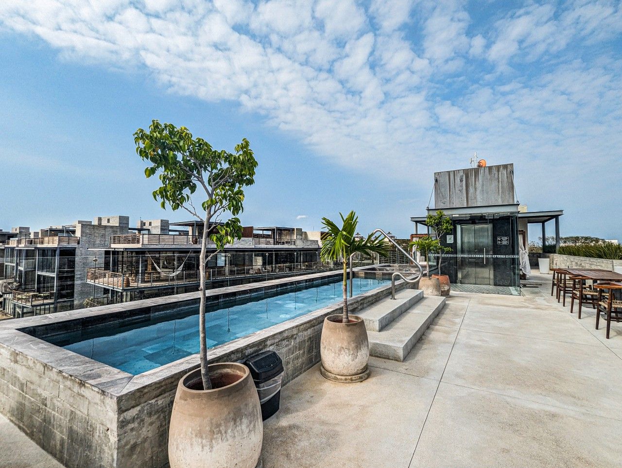 A rooftop pool area with a clear sky, a modern building, and outdoor seating.