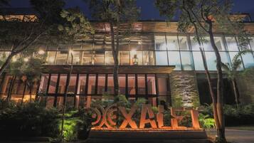 A modern building with a glass facade, surrounded by trees and a well-lit entrance.