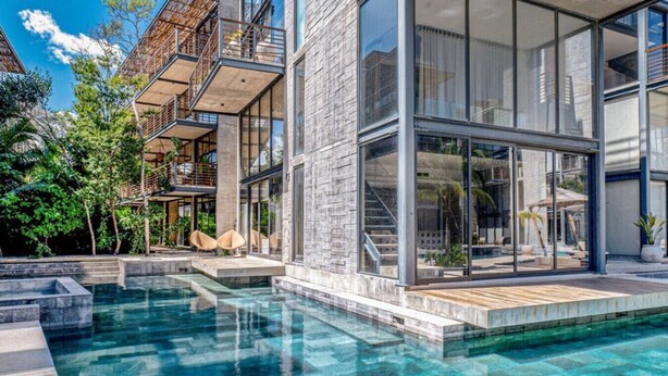 A modern house with a swimming pool, large windows, and outdoor seating. - Nuju Rentals|1Br Penthouse|Jacuzzi, Cenote & Sauna (Tulum)